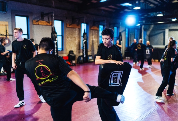 A kickboxer strikes a pad held by a fellow martial arts student.