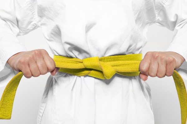 A karate student tightens their yellow belt.