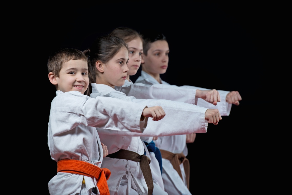 A row of children practicing martial arts throw a punch.