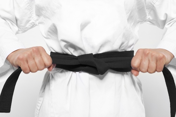A karate student tightens their black belt.