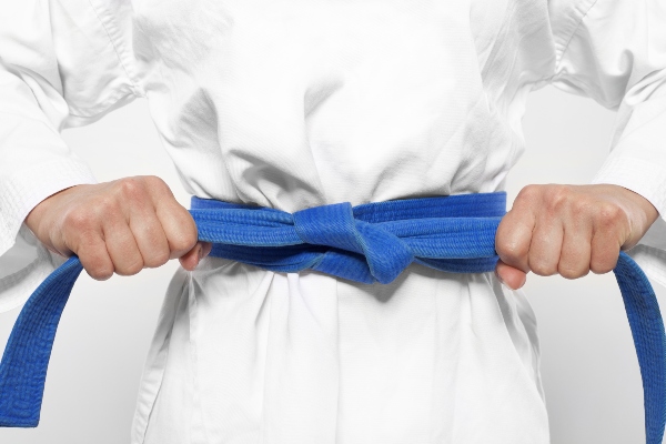 A karate student tightens their blue belt.