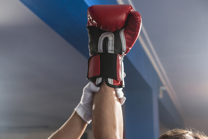 An official holds up the boxing-gloved hand of the fighter who won a match.