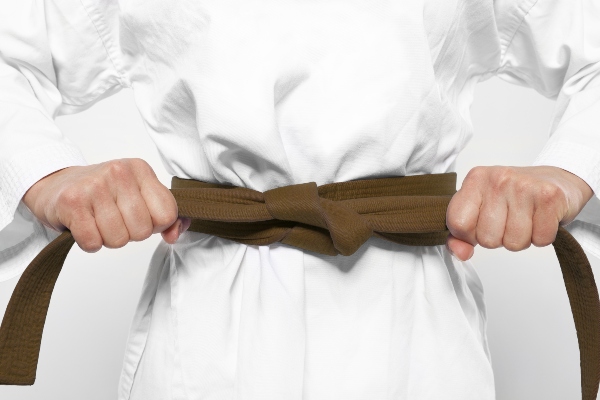 A karate student tightens their brown belt.