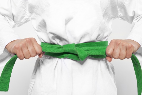 A karate student tightens their green belt.