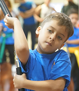 A focused child holding nunchaku at NY Martial Arts Academy