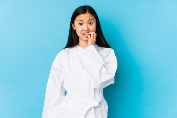 A martial arts child student bites her nails in a state of anxiety.