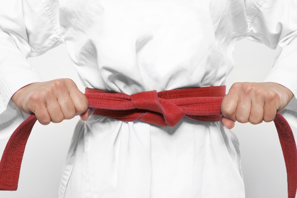 A karate student tightens their red belt.