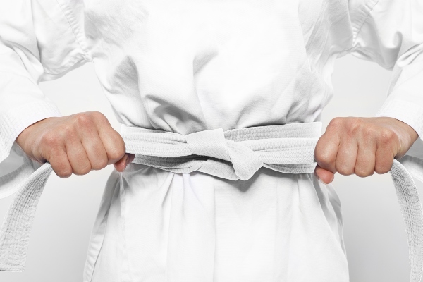 A karate student tightens their white belt.