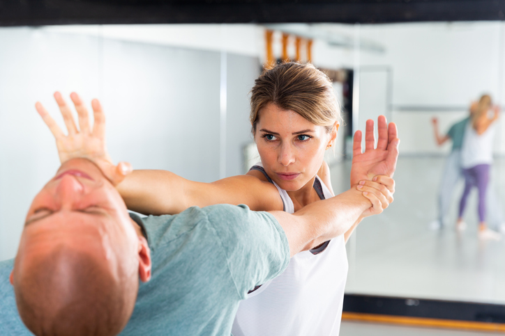 A woman practices a self-defense technique during a martial arts class.
